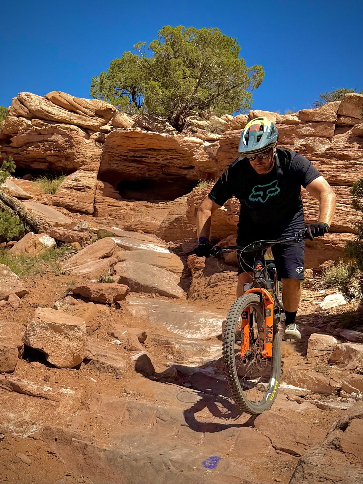 Cole Bangert riding a mountain bike down red sandstone ledges