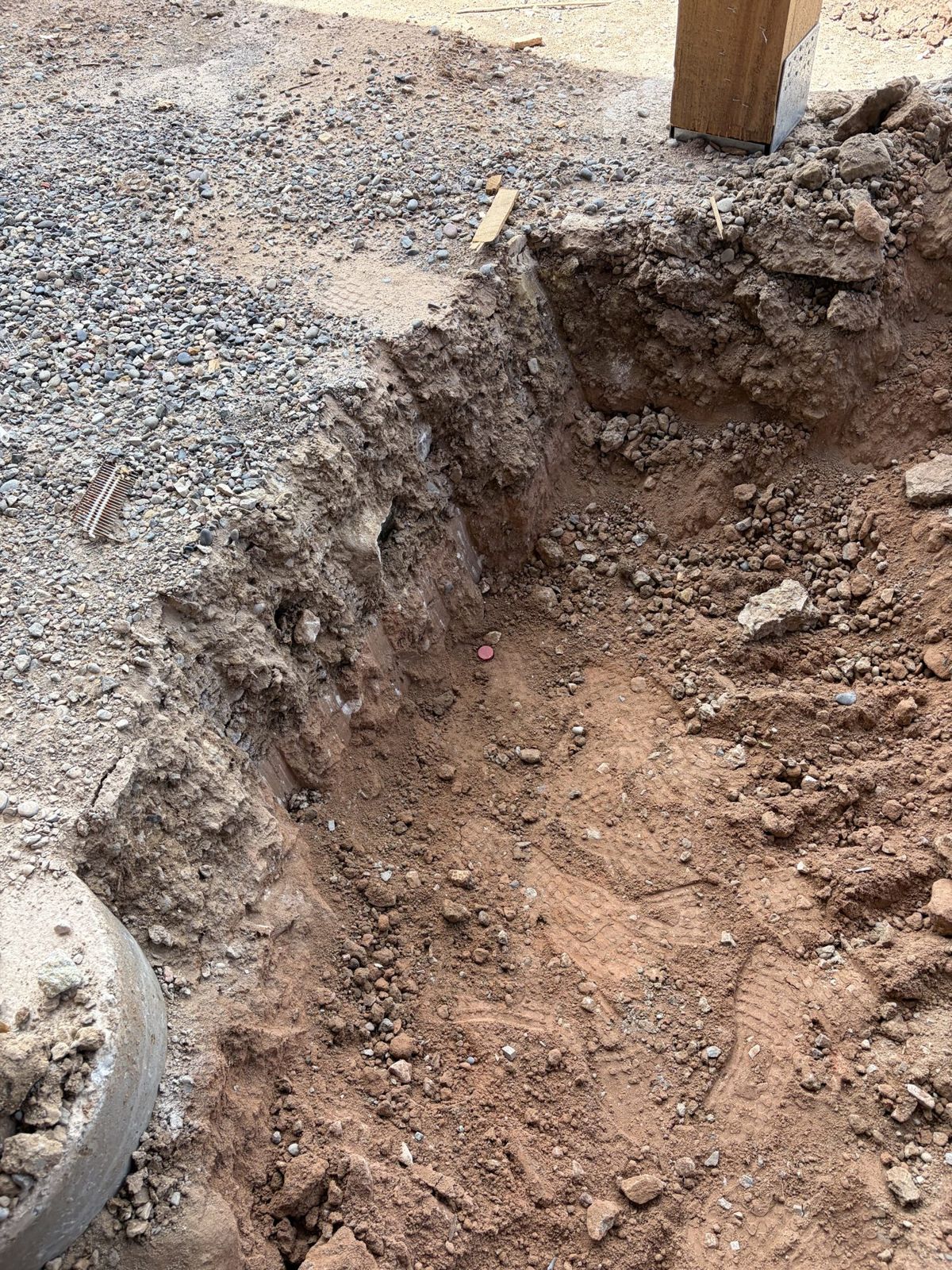An excavation dug alongside an existing structure and gravel base